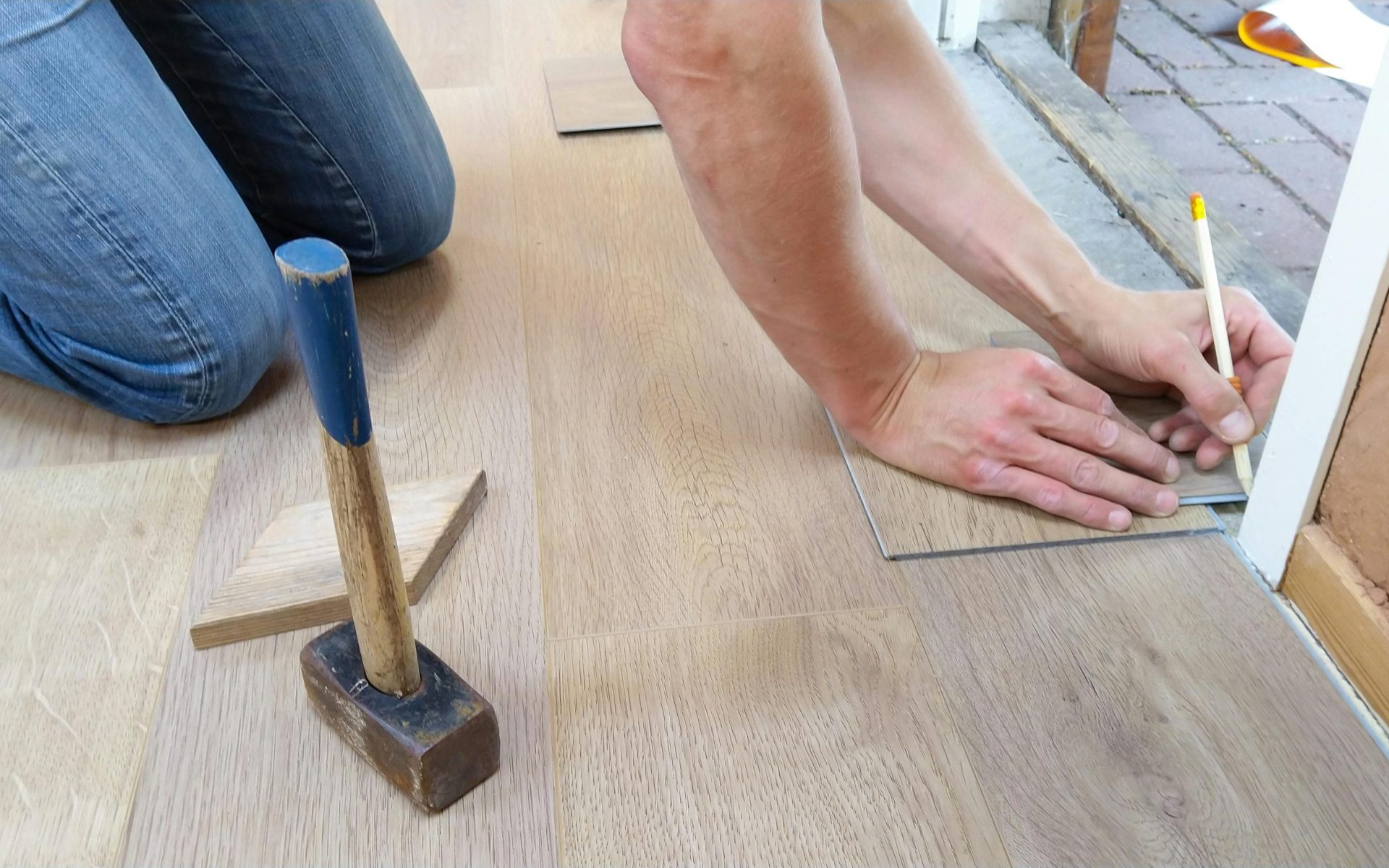 A craftsman carefully measures and marks wooden floor panels for precise installation.